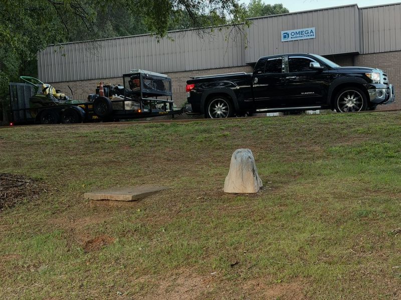 Black pickup truck and open trailer loaded with zero-turn mowers parked at a commercial job site